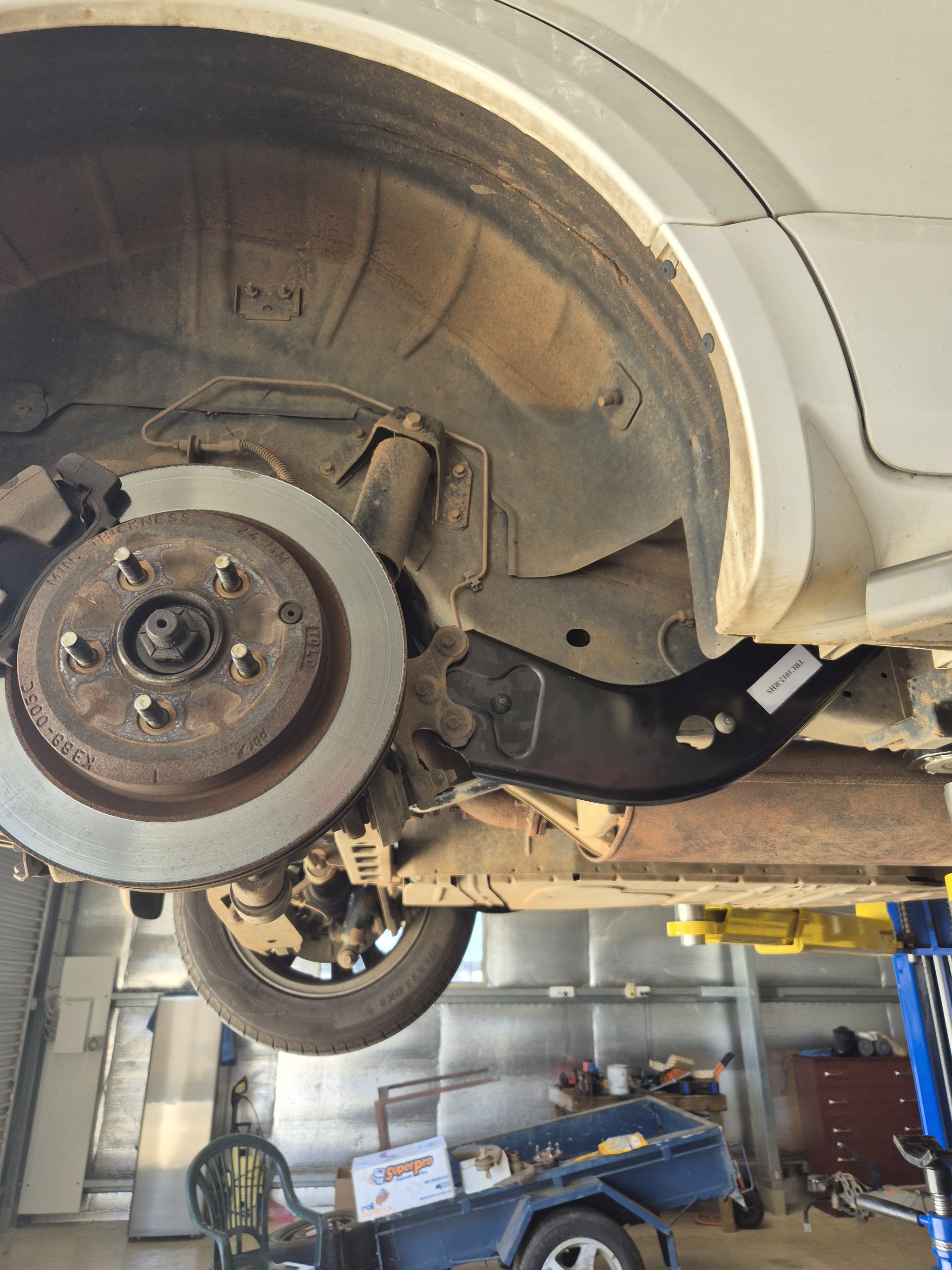 A car raised on the two post hoist in the workshop, brakes and suspension in view